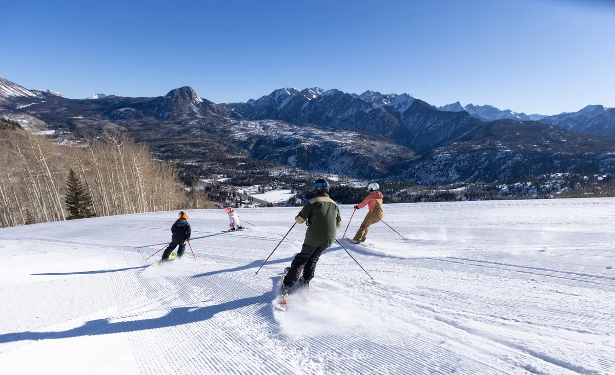 Snow-covered mountain slopes with skiers in action, framed by distant peaks. The scene captures the exhilarating spirit of winter sports and the natural beauty of the alpine environment. The crisp white snow and dynamic movement evoke adventure and excitement.