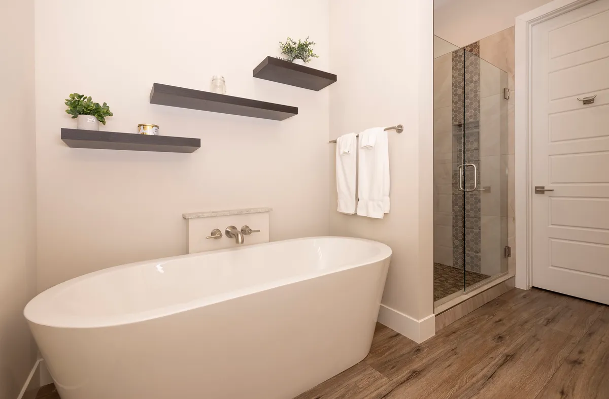 A luxurious bathroom featuring a freestanding soaking tub, a glass-enclosed shower, and modern floating shelves. The calm, spa-like ambiance is perfect for relaxation and self-care after a day of mountain adventures.