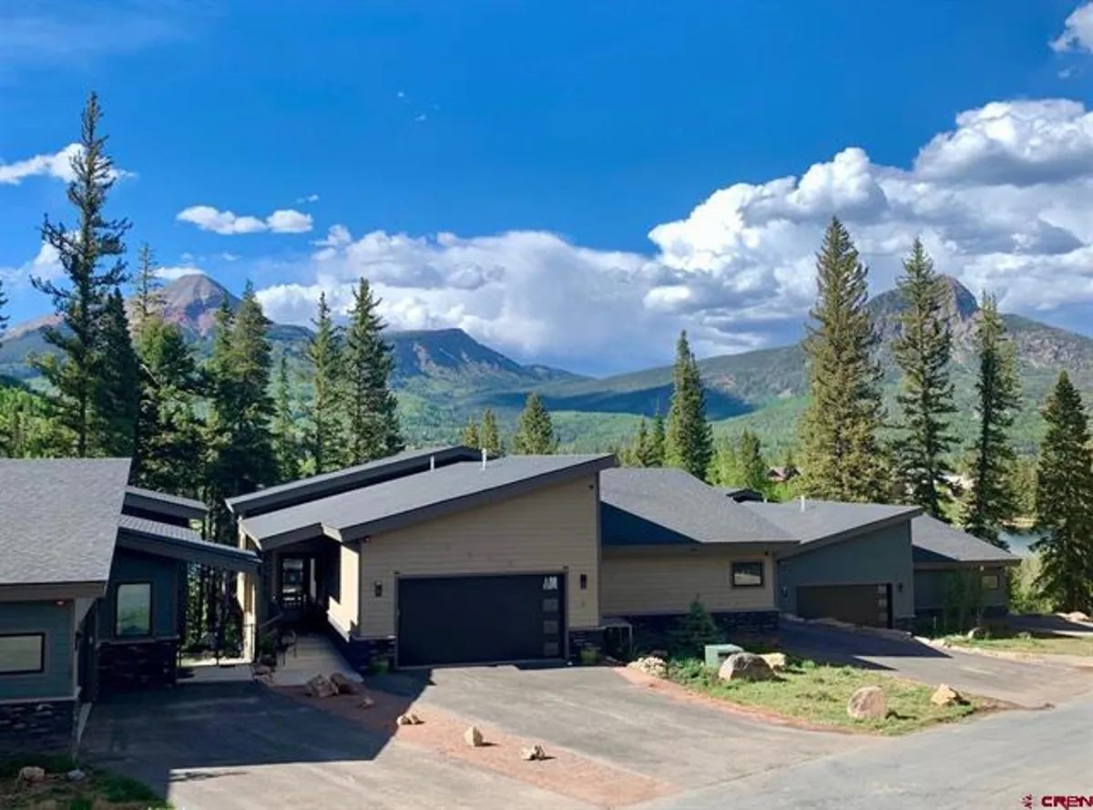 Modern resort architecture surrounded by tall, lush trees and a majestic mountain backdrop, with hints of golden light suggesting sunset or early evening. The peaceful scene beckons outdoor exploration and relaxation, emphasizing connection to nature.