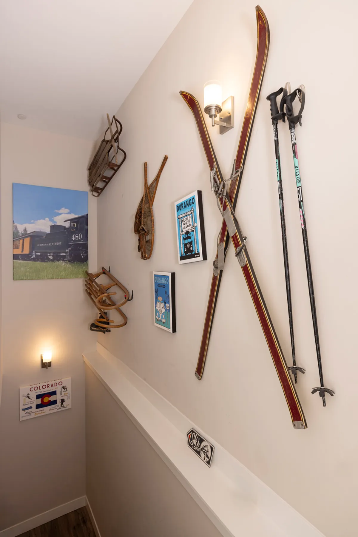 A charming interior vignette featuring vintage skis, ski poles, wall art, and colorful sleds displayed on the wall, evoking a nostalgic alpine vibe. The scene hints at adventures awaiting just outside, connecting the home to the winter activities nearby.