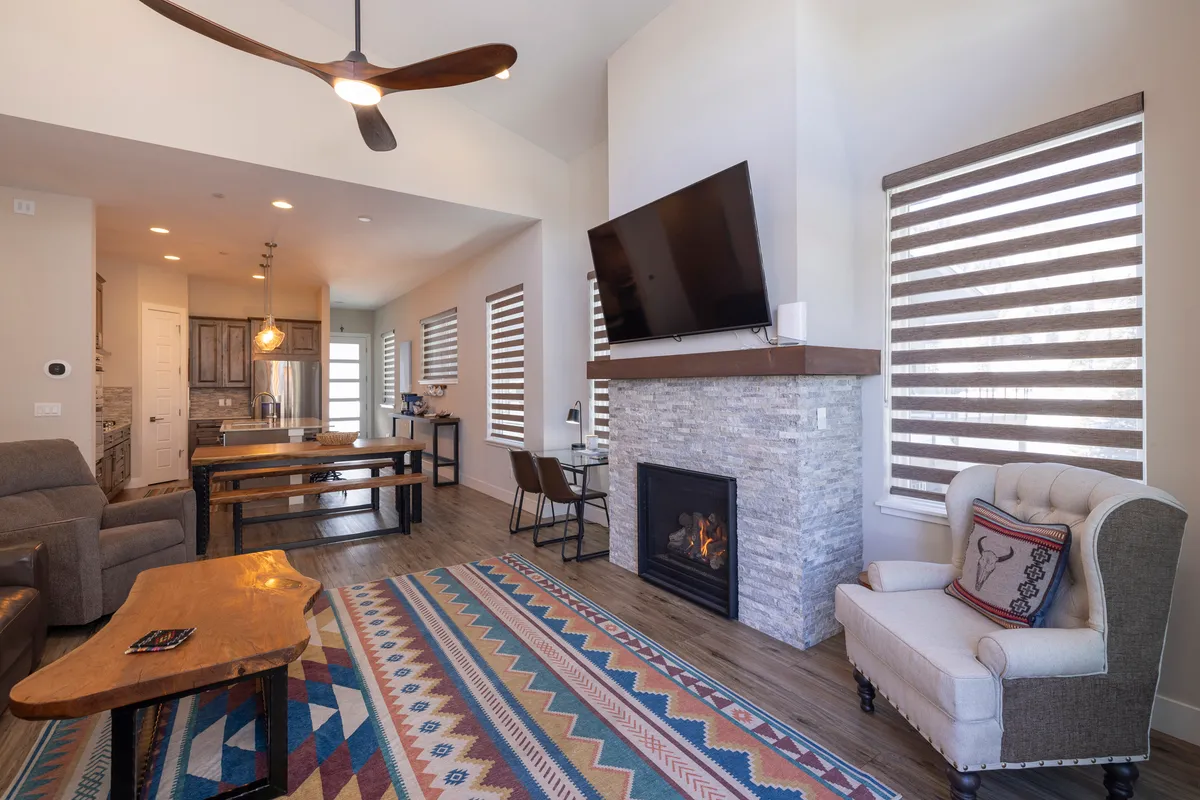 A warm, inviting living space with a glowing fireplace, cozy rug, comfortable sofa, and a dining table, perfect for gathering after a day of outdoor adventure. The ambiance is relaxing and home-like, ideal for families and groups.
